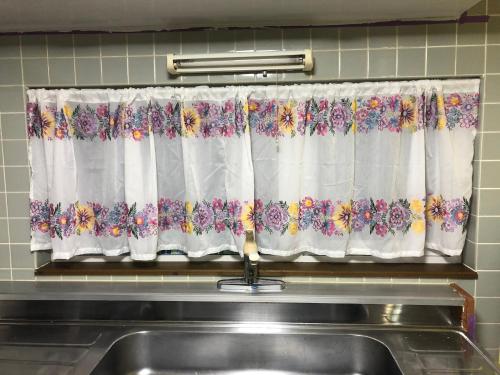 a kitchen window with a curtain with flowers on it at STAY Sakura in Bibai