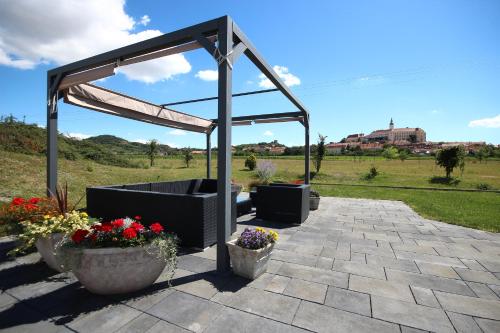 a pergola with flowers in pots on a patio at Hotel Maroli Mikulov in Mikulov