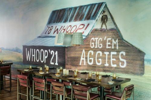 a dining room with a table and a barn mural at Texas A&M Hotel and Conference Center in College Station