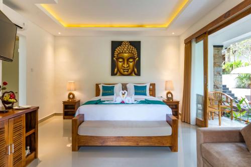 a bedroom with a bed with a large mask on the wall at The Pesaren Ubud in Ubud