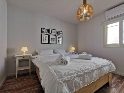 a white bedroom with a large bed with towels on it at Eilat vacation house דירות נופש אילת in Eilat