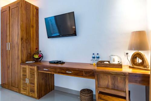 a wooden desk with a television on a wall at The Pesaren Ubud in Ubud