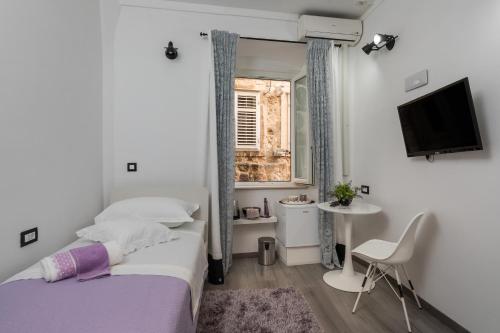 ein Schlafzimmer mit einem Bett, einem Fernseher und einem Fenster in der Unterkunft Guest House Tomasi One in Dubrovnik