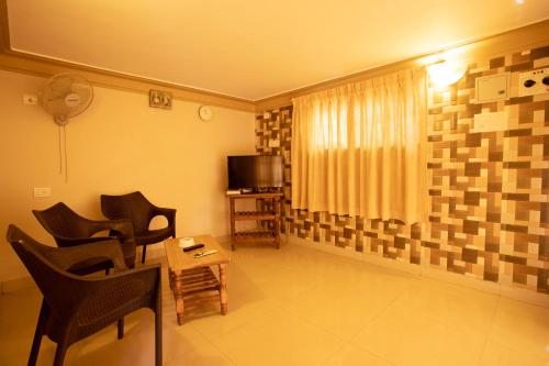 a living room with chairs and a television and a table at Casa Margarida in Calangute