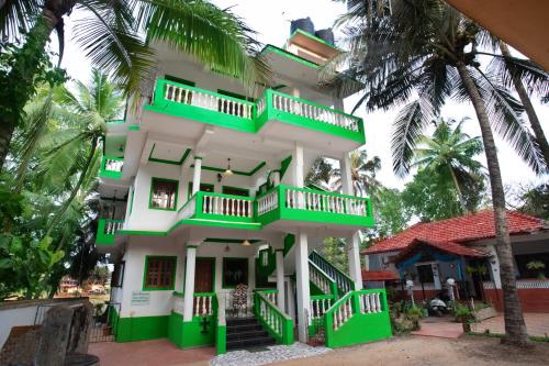 a green and white building with palm trees at Casa Margarida in Calangute