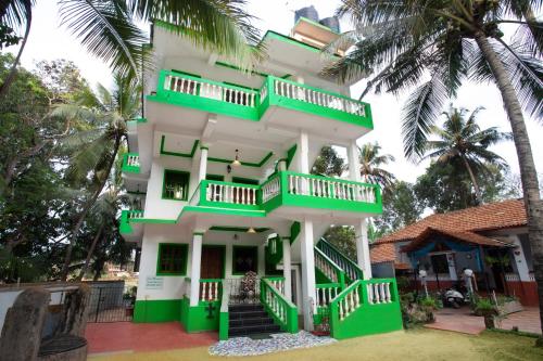 a green and white building with palm trees at Casa Margarida in Calangute