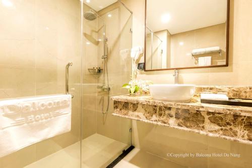 a bathroom with a sink and a shower with a mirror at Balcona Hotel Da Nang in Da Nang