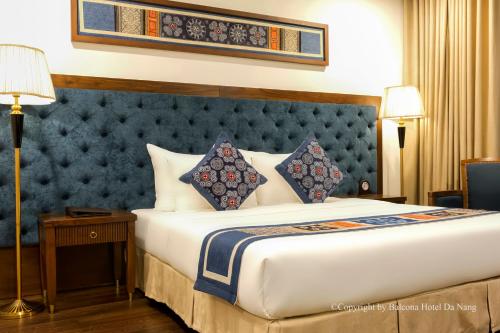 a bedroom with a large bed with a blue headboard at Balcona Hotel Da Nang in Da Nang