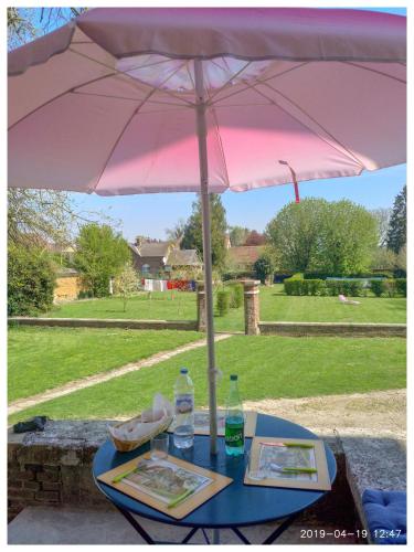 a table with a pink umbrella on top of it at Fief des 3 Guillaume Chambres d'hôtes in Écouis