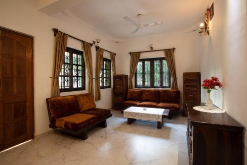 a living room with couches and a table and windows at Casa Margarida in Calangute