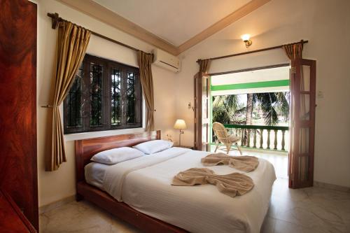 a bedroom with a bed with a window and a chair at Casa Margarida in Calangute