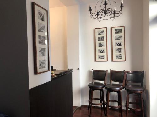 a dining room with three bar stools and a chandelier at Casa Mignon in Oradea