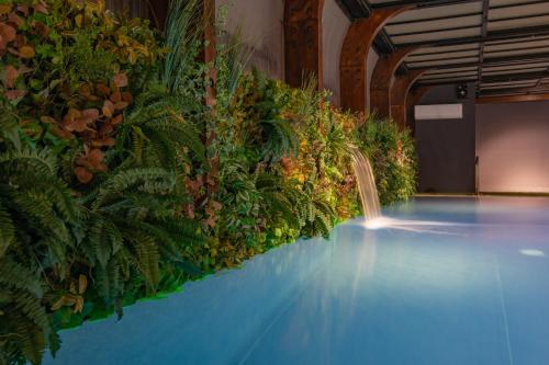 a pool with a waterfall and plants on the wall at Well Hotel & Spa in Maceira