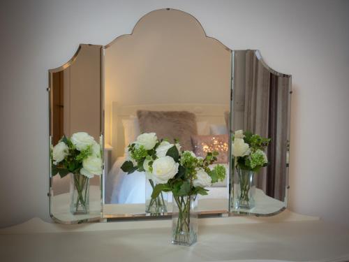 a mirror with two vases with white flowers in it at Taymore Lodge in Kenmore
