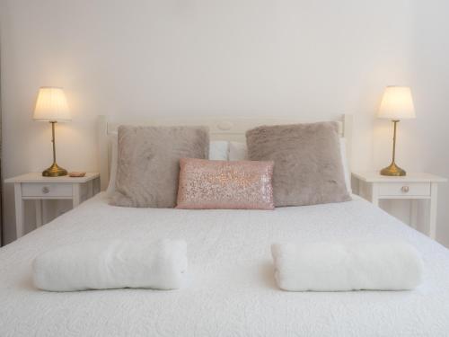 a white bed with two pillows on it with two lamps at Taymore Lodge in Kenmore