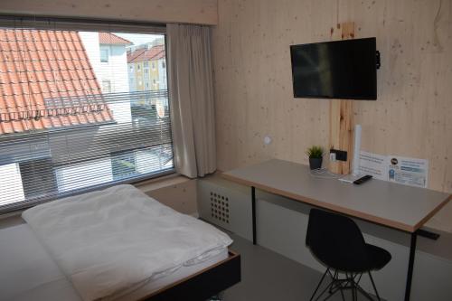 een kamer met een bed, een bureau en een raam bij NewAge Boardinghaus N70 in Heilbronn