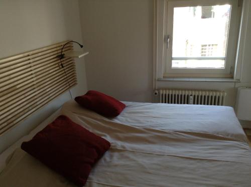 City Hotel Appartement Tilburg في تيلبورغ: غرفة نوم بها سرير ووسادتين حمرا