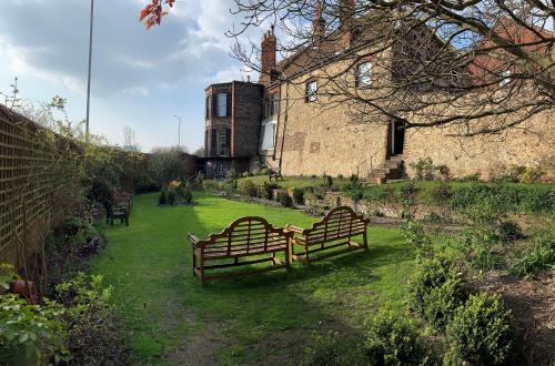 two benches sitting in the grass in front of a building at Castle House Hotel in Canterbury