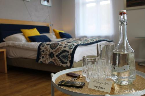 a table with a bottle and glasses on it with a bed at Dworek Zakopane in Zakopane