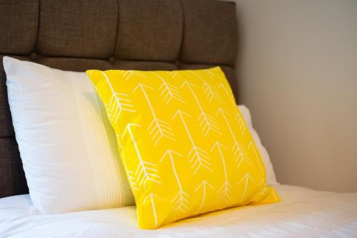 a yellow pillow sitting on top of a bed at 3 Bedrooms, Parking & Courtyard in Swansea