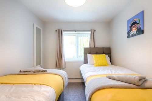 two beds in a small room with a window at 3 Bedrooms, Parking & Courtyard in Swansea