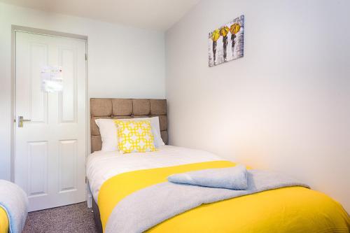 a small bedroom with a yellow and white bed at 3 Bedrooms, Parking & Courtyard in Swansea