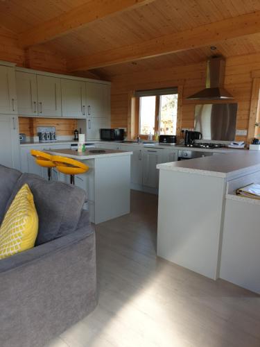 a kitchen with white cabinets and a couch in a room at Ruth's Retreat Shropshire Countryside Lodge with private hot tub & great views in Shrewsbury