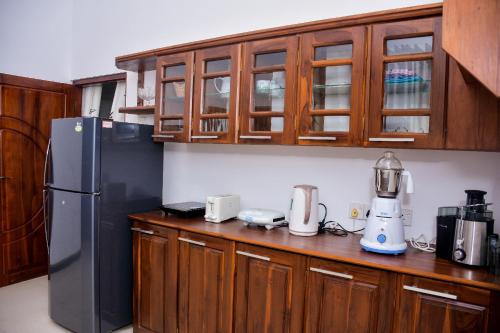 a kitchen with wooden cabinets and a black refrigerator at CASA VACANSA HOME STAY in Hungama