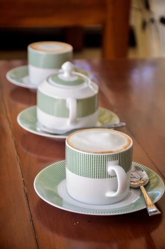 three cups of coffee sitting on a wooden table at CASA VACANSA HOME STAY in Hungama
