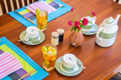 a wooden table with plates and pitchers of tea and flowers at CASA VACANSA HOME STAY in Hungama