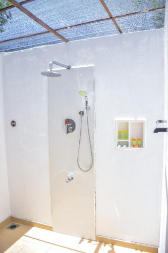 a bathroom with a shower in a white wall at CASA VACANSA HOME STAY in Hungama