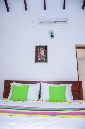 a bedroom with a bed with green and white pillows at CASA VACANSA HOME STAY in Hungama