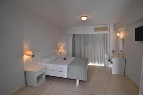 a bedroom with a white bed and a bathroom at Evripides Village in Kardamaina