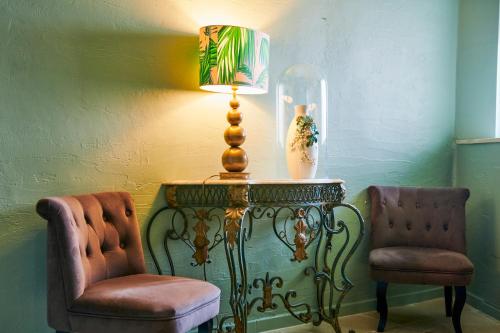 a lamp sitting on a table next to two chairs at Logis Hôtel Restaurant Le Plantevin in Propiac