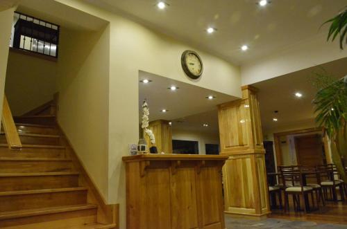 a lobby with a clock on the wall and stairs at Alma Andina Hosteria in Villa La Angostura