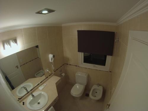 a bathroom with a sink and a toilet and a television at Alma Andina Hosteria in Villa La Angostura