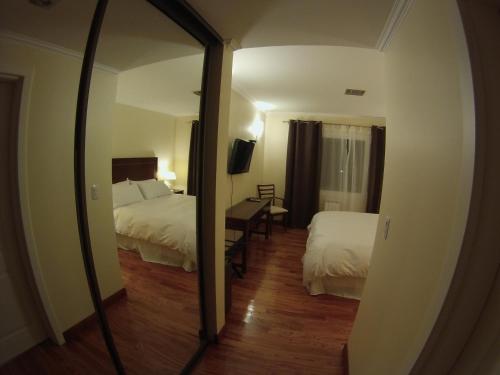 a hotel room with two beds and a mirror at Alma Andina Hosteria in Villa La Angostura