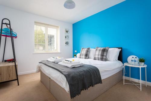 a bedroom with blue walls and a bed with towels on it at Lloyd Close Cheltenham - Close to Town Centre & GCHQ in Cheltenham