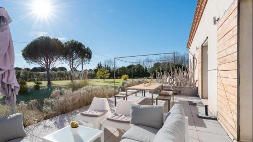 a patio with white couches and tables and trees at Mas Sainte Marie ,Piscine Chauffée in Aigues-Mortes