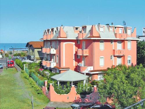 un grande edificio rosa con una recinzione di fronte ad esso di lorecasa a Porto Garibaldi