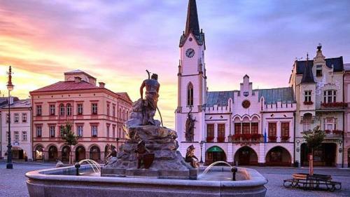 a statue in front of a building with a clock tower at Apartmán Dračí údolí in Trutnov