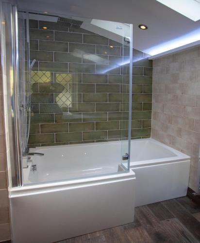 a bathroom with a tub and a glass shower at Aberdunant Hall in Porthmadog