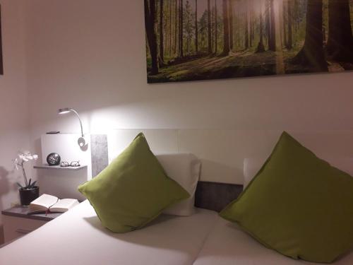 two green pillows sitting on a bed in a room at GÄSTEHAUS LIFESTYLE in Kirrweiler
