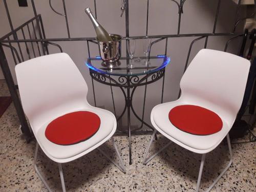 two white chairs and a glass table with a bottle on it at GÄSTEHAUS LIFESTYLE in Kirrweiler