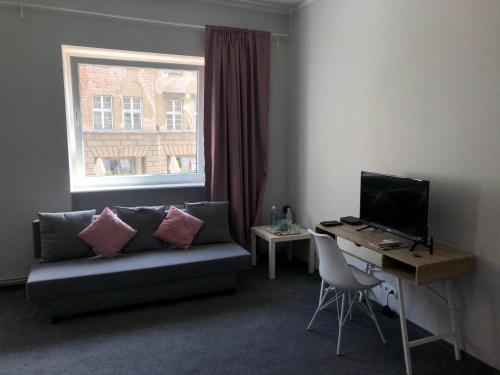 - un salon avec un canapé et un bureau avec un ordinateur dans l'établissement Pokoje na Pańskiej 9, à Gdańsk