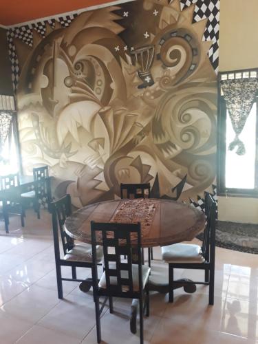 a table and chairs in a room with a mural at Sumatra Cheeky Monkeys in Bukit Lawang