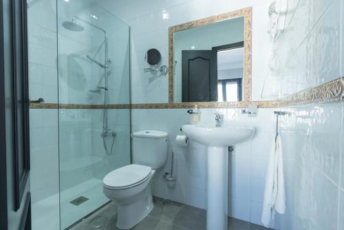 een badkamer met een toilet, een wastafel en een spiegel bij Hostal El Yunque in Conil de la Frontera