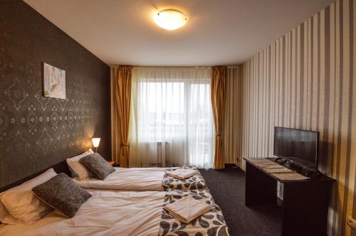 a hotel room with two beds and a television at Elite Spetema Hotel in Sofia