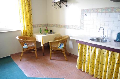 uma cozinha com uma mesa e cadeiras e um lavatório em La Petite Provence em Leisnig