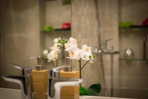 a bathroom sink with a white orchid in a holder at First Floor Flat in Ljubljana